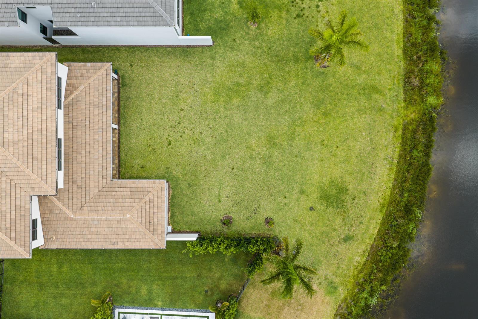 An aerial view shows a house with a tiled roof, a large lawn, and a pond — 20028 Pacific Dunes Drive, Boca Raton FL 33434, BOCA RATON, FL