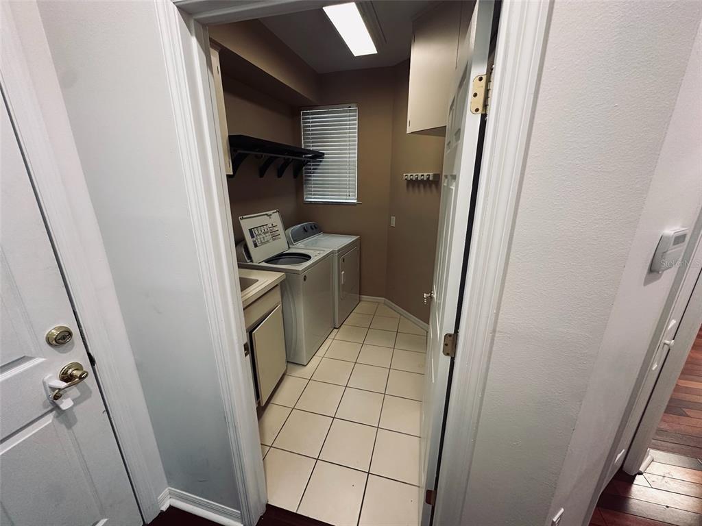 A laundry room with tile flooring, a washer and dryer, and upper cabinetry — 3125 STONEWATER DRIVE, LAKELAND, FL