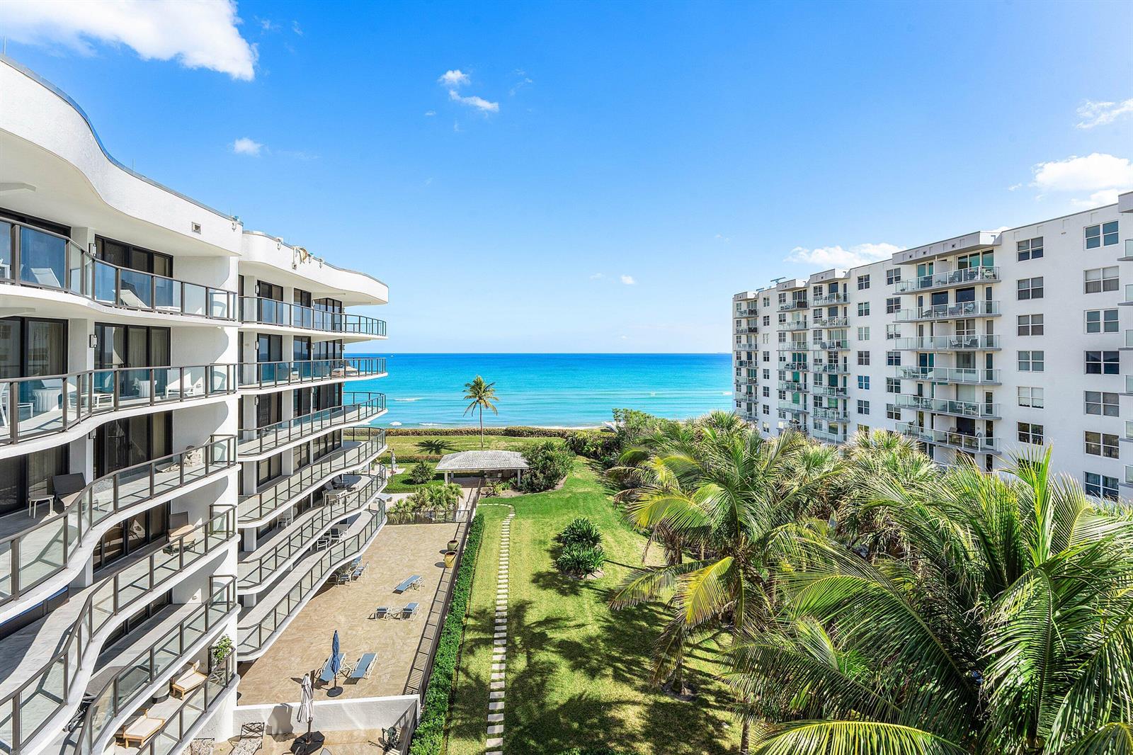 An elevated view shows two white apartment buildings flanking a grassy courtyard leading to the ocean — 3440 S Ocean Boulevard NE # 608s, Palm Beach FL 33480, PALM BEACH, FL