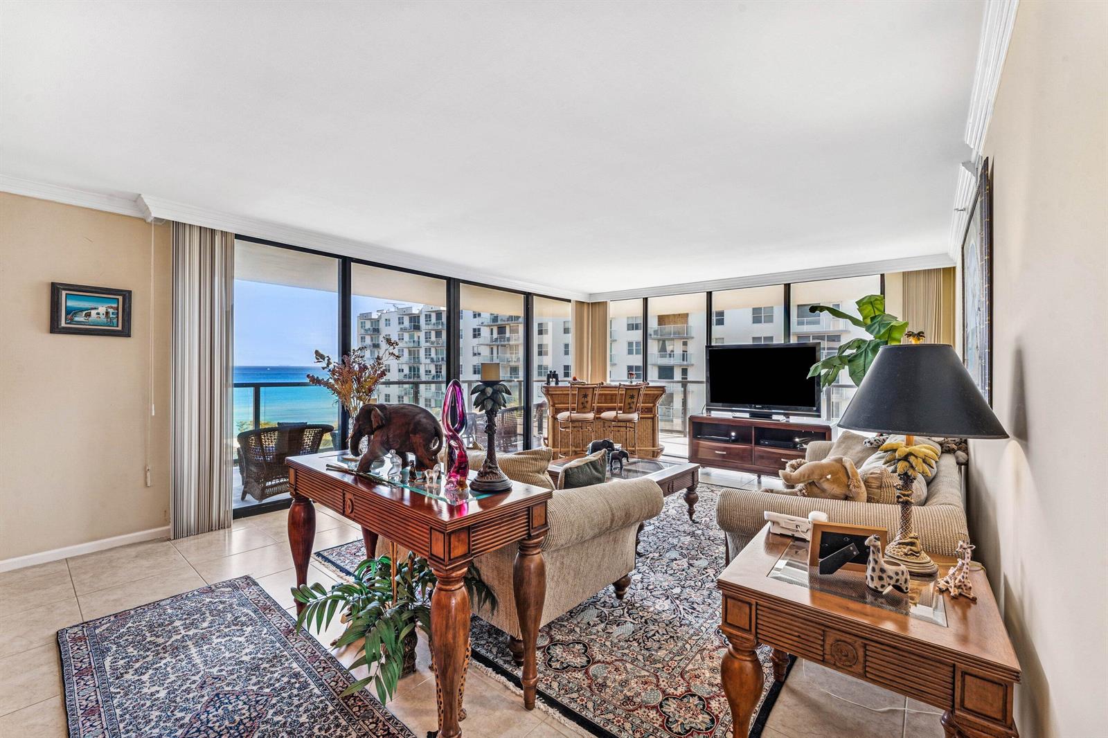 A living room features a sofa, a wooden console table, and floor-to-ceiling windows with ocean views — 3440 S Ocean Boulevard NE # 608s, Palm Beach FL 33480, PALM BEACH, FL