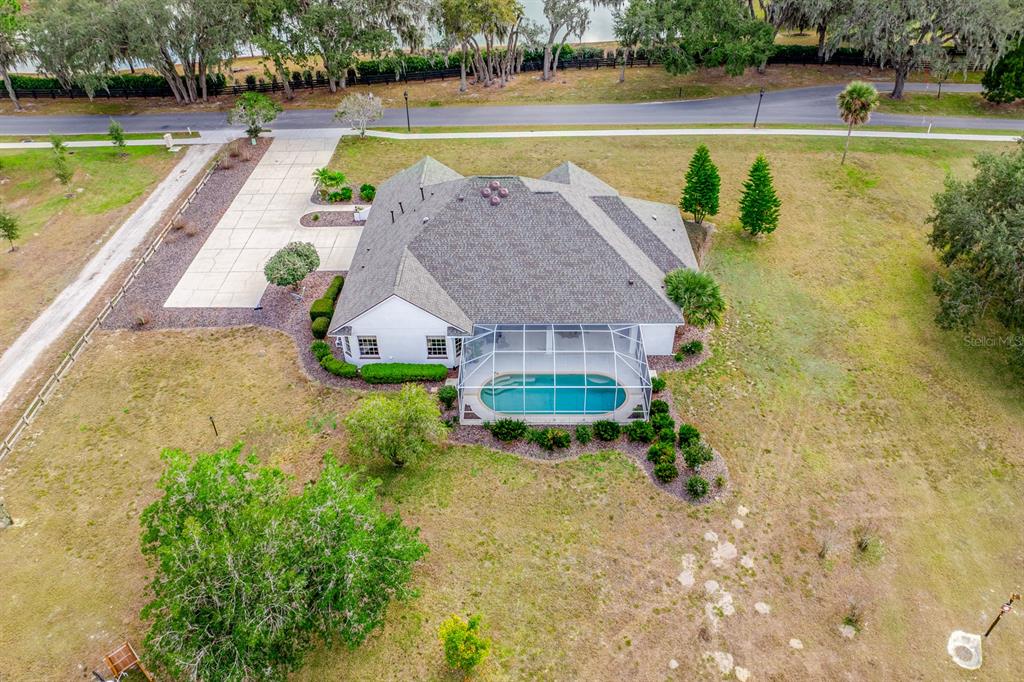 An aerial view shows a house with a screened-in pool and a large concrete driveway — 5092 NE 81ST BOULEVARD, WILDWOOD, FL