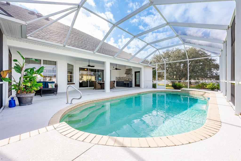 A screened-in patio features a swimming pool, outdoor kitchen, and covered seating area — 5092 NE 81ST BOULEVARD, WILDWOOD, FL