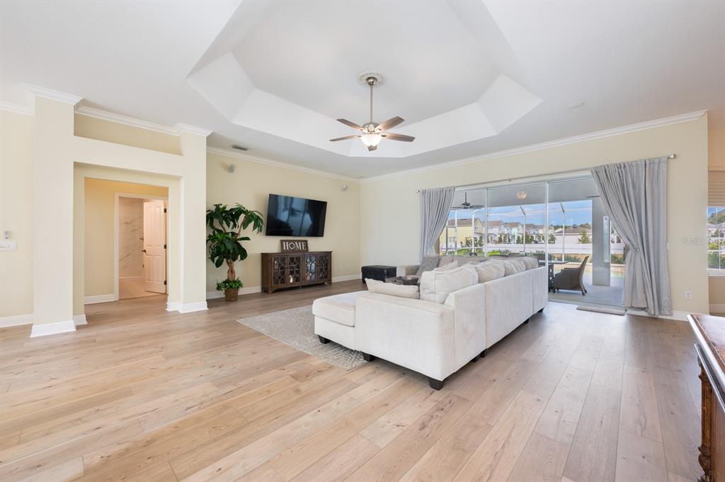 A spacious living room features light wood flooring, a tray ceiling, and sliding glass patio doors — 5092 NE 81ST BOULEVARD, WILDWOOD, FL