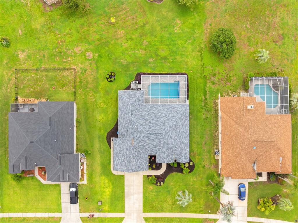 An aerial view shows three suburban houses with pools and driveways on a grassy lot — 14074 ANDREW SCOTT ROAD, SPRING HILL, FL