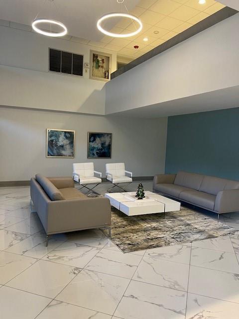 A modern lobby features white marble floors, two grey sofas, and two white accent chairs — 531 N Ocean Boulevard # 1808, Pompano Beach FL 33062, POMPANO BEACH, FL