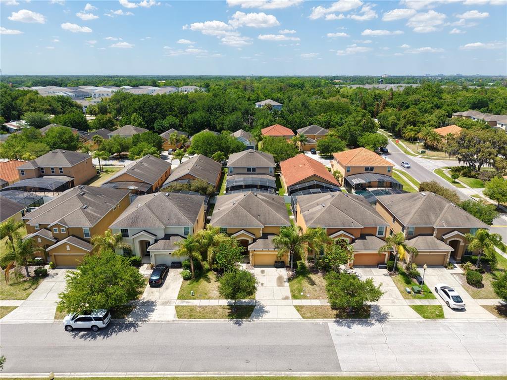 An aerial view shows a row of suburban houses with driveways and screened-in back patios — 2549 DHARMA CIRCLE, KISSIMMEE, FL