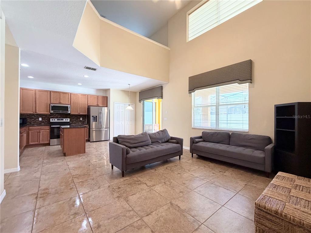 An open-concept living room and kitchen featuring tile floors, high ceilings, and two sofas — 2549 DHARMA CIRCLE, KISSIMMEE, FL