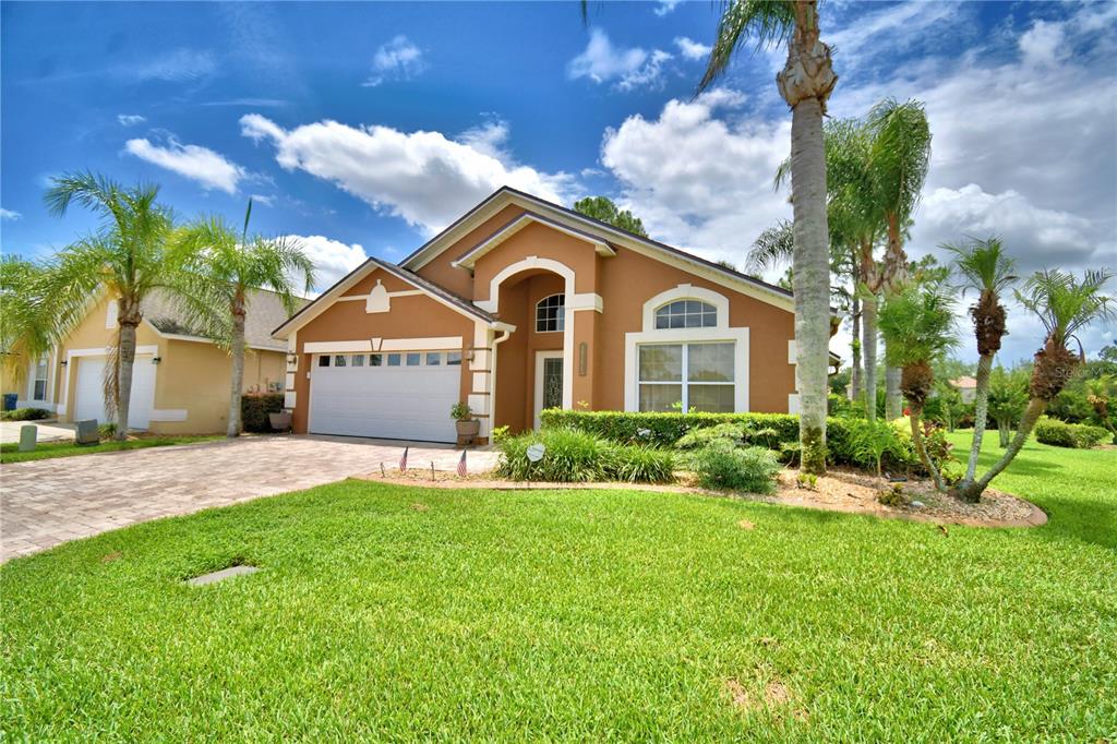 A single-story tan house with a two-car garage, arched entryway, and palm trees in front — 2701 KOKOMO LOOP, HAINES CITY, FL