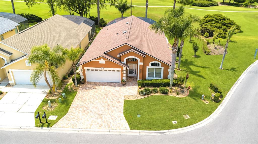 An aerial view shows a single-story orange house with a paved driveway and palm trees — 2701 KOKOMO LOOP, HAINES CITY, FL