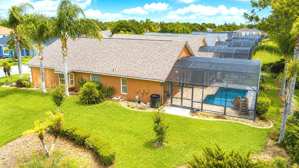 An aerial view of a tan house with a screened-in pool and backyard landscaping — 2701 KOKOMO LOOP, HAINES CITY, FL
