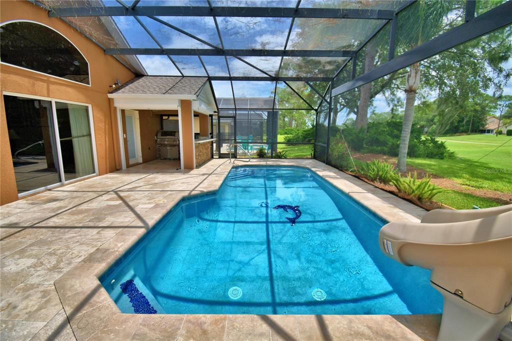 A screened-in patio features a swimming pool with a slide and an outdoor kitchen area — 2701 KOKOMO LOOP, HAINES CITY, FL