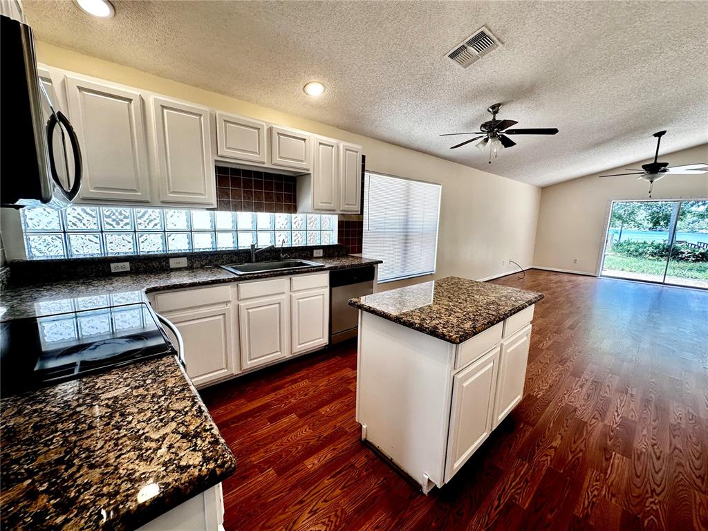 A kitchen with white cabinets, granite countertops, a glass block backsplash, and hardwood flooring — 9217 TELFER RUN, ORLANDO, FL