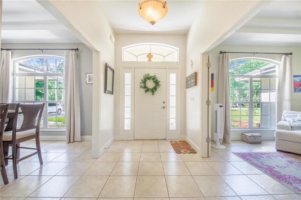 A bright entryway features tiled floors, a white front door with sidelights, and arched windows — 7152 FUSSELL ROAD, POLK CITY, FL