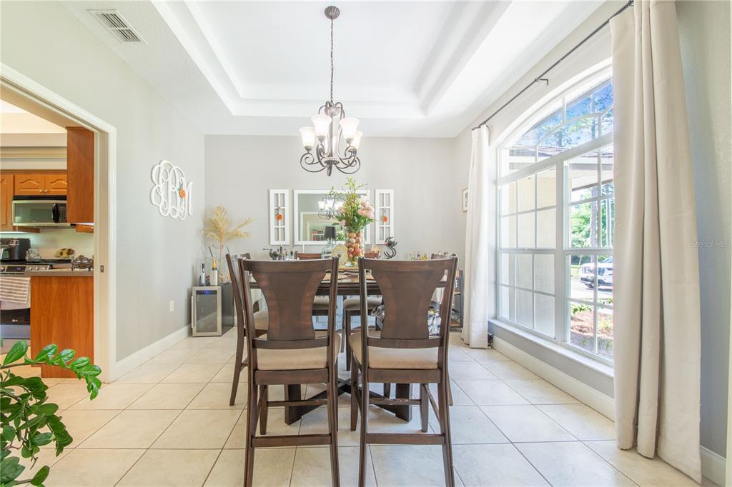 A dining room features a dark wood table and chairs under a chandelier near windows — 7152 FUSSELL ROAD, POLK CITY, FL
