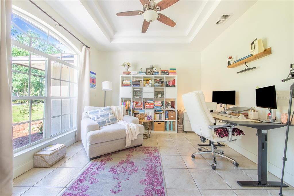 A home office with a white bookshelf, a desk, a chair, and a large window — 7152 FUSSELL ROAD, POLK CITY, FL