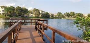 A wooden pier extends over a lake toward residential buildings in the background — 250 Jacaranda Dr # 305, Plantation FL 33324, PLANTATION, FL