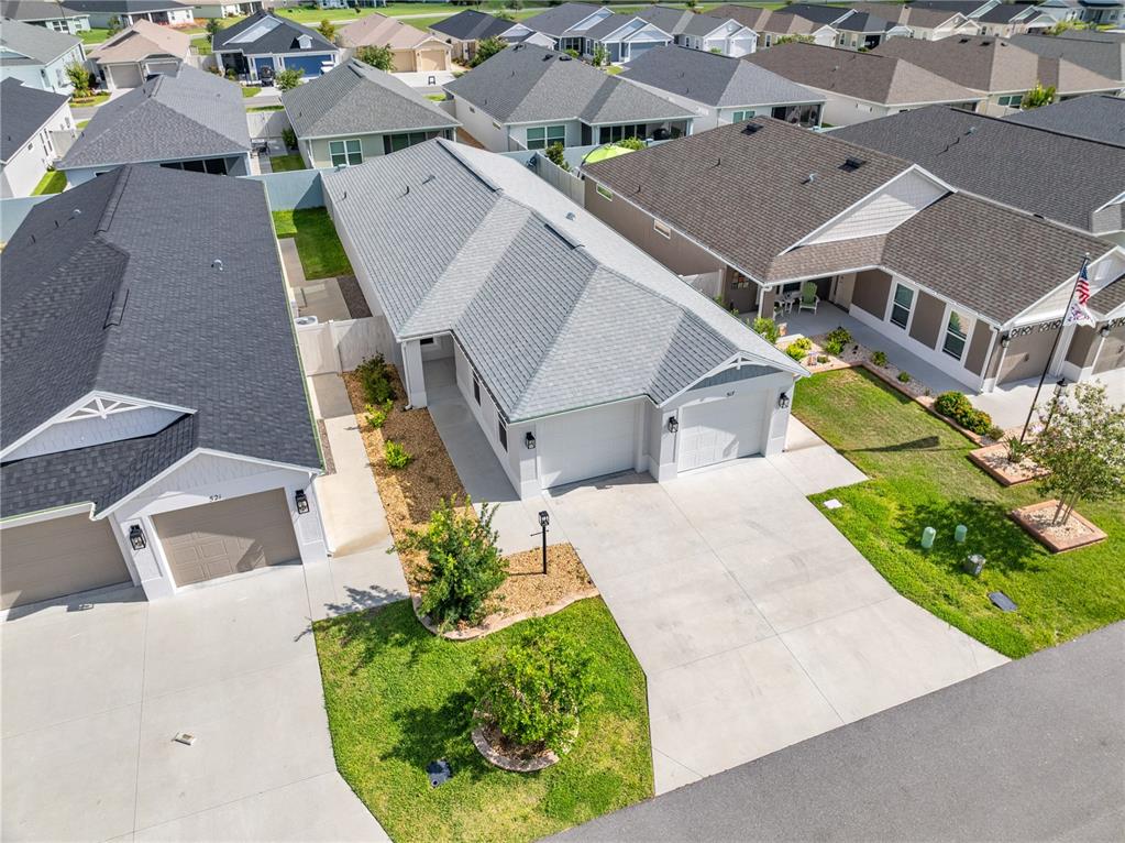 An aerial view shows two adjacent suburban houses with gray roofs, concrete driveways, and lawns — 517 LAMINGTON LANE, THE VILLAGES, FL