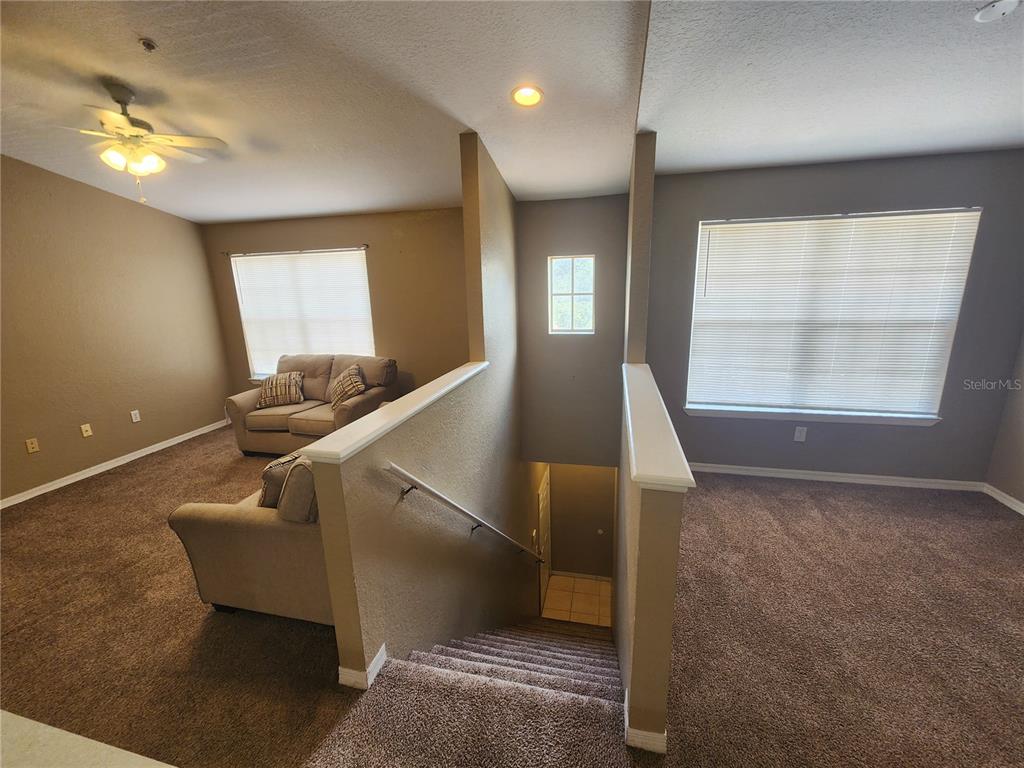 A carpeted staircase leads up to a landing between two carpeted living areas — 821 GRAND REGENCY POINTE UNIT 203, ALTAMONTE SPRINGS, FL