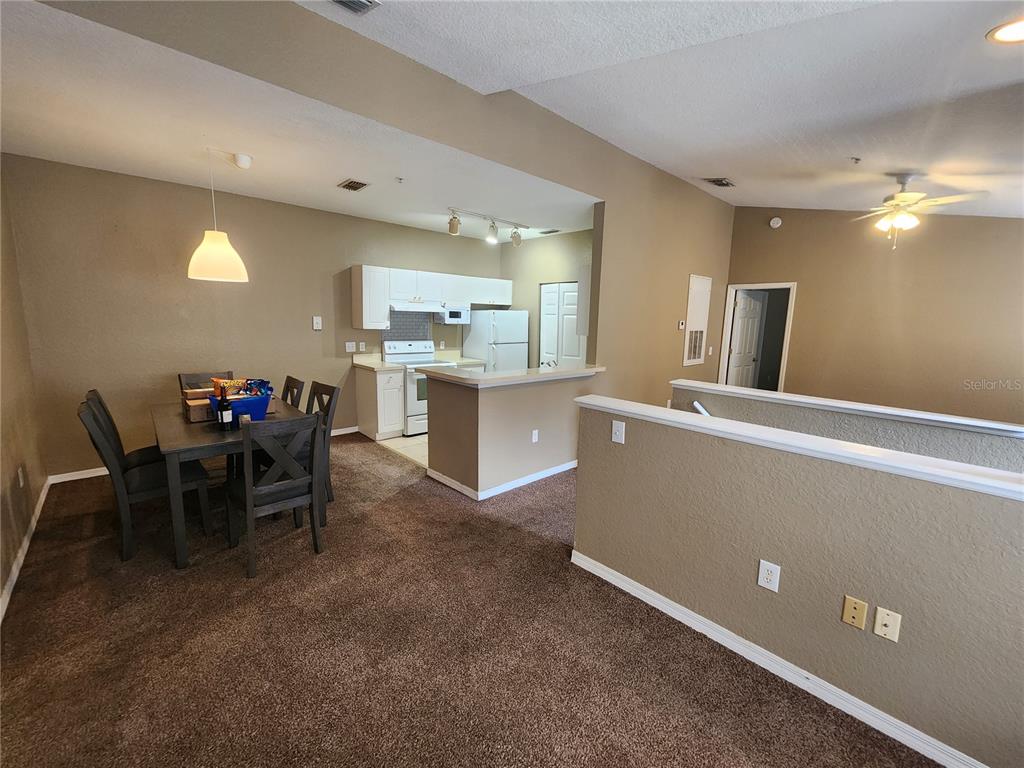 An open-concept dining area and kitchen with brown carpet and tan walls — 821 GRAND REGENCY POINTE UNIT 203, ALTAMONTE SPRINGS, FL