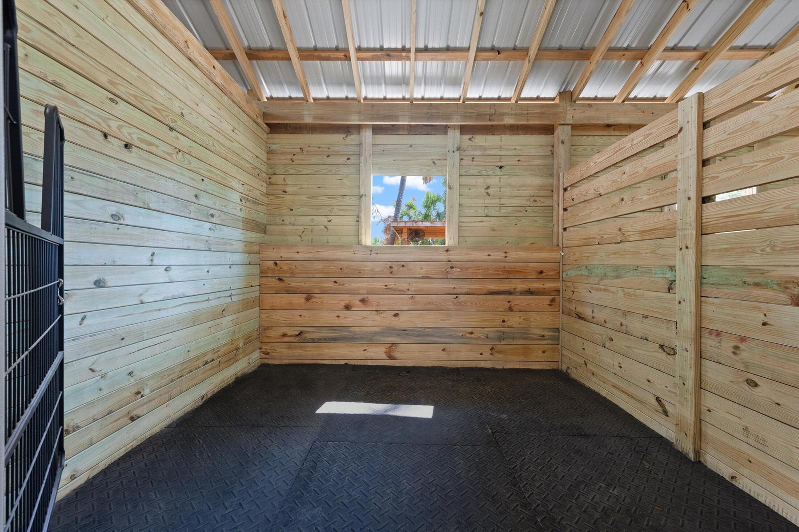 A horse stall with wood-paneled walls, a rubber mat floor, and an open-air window — 3509 C Road, FL 33470, FL