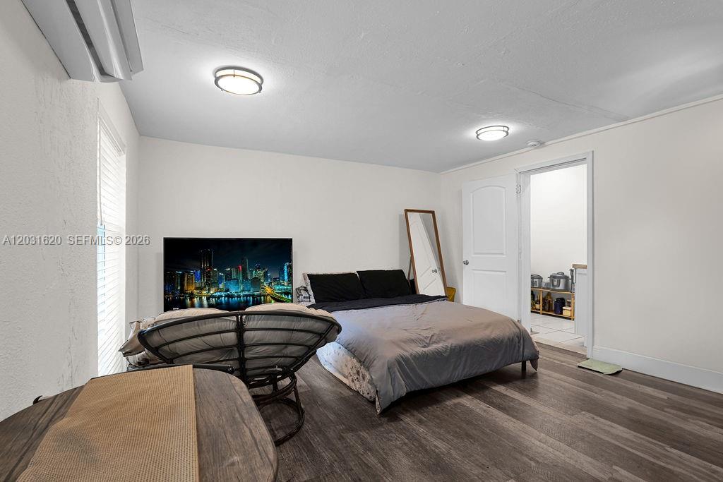 A bedroom features a bed, a papasan chair, a television, and wood-look flooring — 3010 NW 95th Ter # A, Miami FL 33147, MIAMI, FL