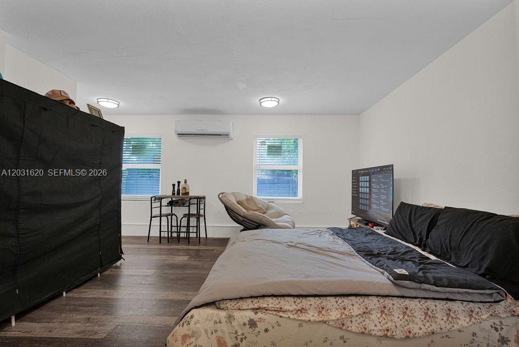 A bedroom features wood-look flooring, a bed, a television, a small dining set, and a wardrobe — 3010 NW 95th Ter # A, Miami FL 33147, MIAMI, FL