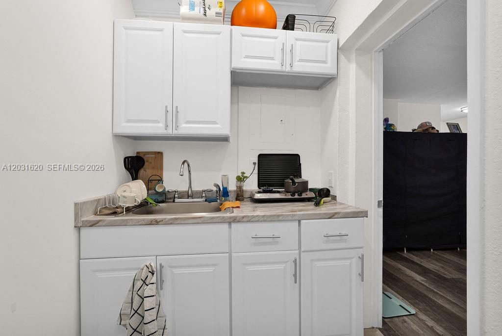 A small kitchen features white cabinets, a stainless steel sink, and a marble-patterned countertop — 3010 NW 95th Ter # A, Miami FL 33147, MIAMI, FL