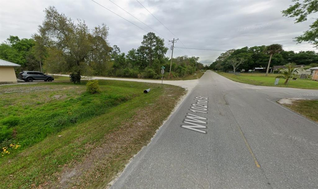 A paved road with a street sign intersection and a grassy area with trees — 10234 N CENTER AVENUE, OKEECHOBEE, FL