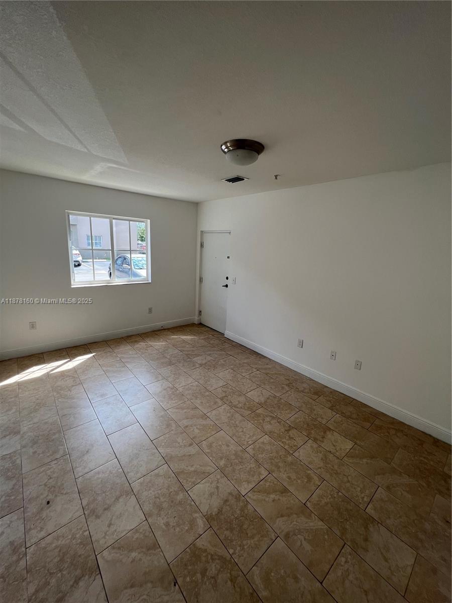 An empty room features white walls, a single window, and light-colored tile flooring — 211 W 79th Pl # 302, Hialeah FL 33014, HIALEAH, FL