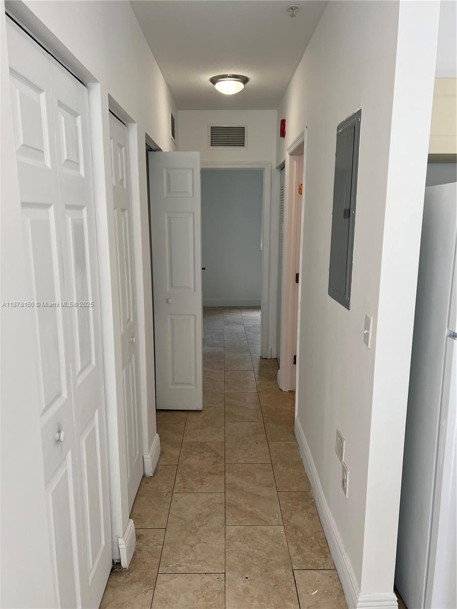 A narrow hallway features beige tile flooring, white doors, and a recessed ceiling light — 211 W 79th Pl # 302, Hialeah FL 33014, HIALEAH, FL