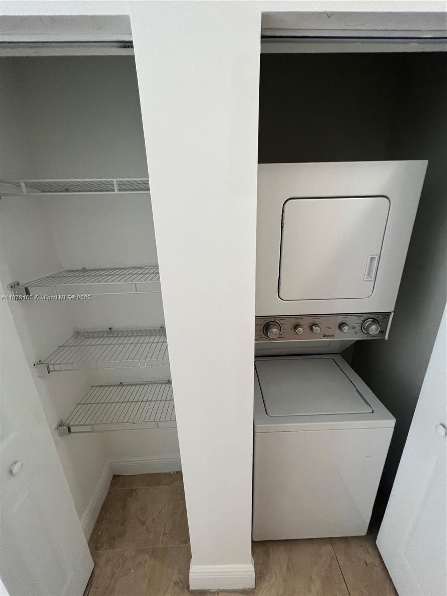 A closet contains white wire shelving next to a stacked white washer and dryer unit — 211 W 79th Pl # 302, Hialeah FL 33014, HIALEAH, FL