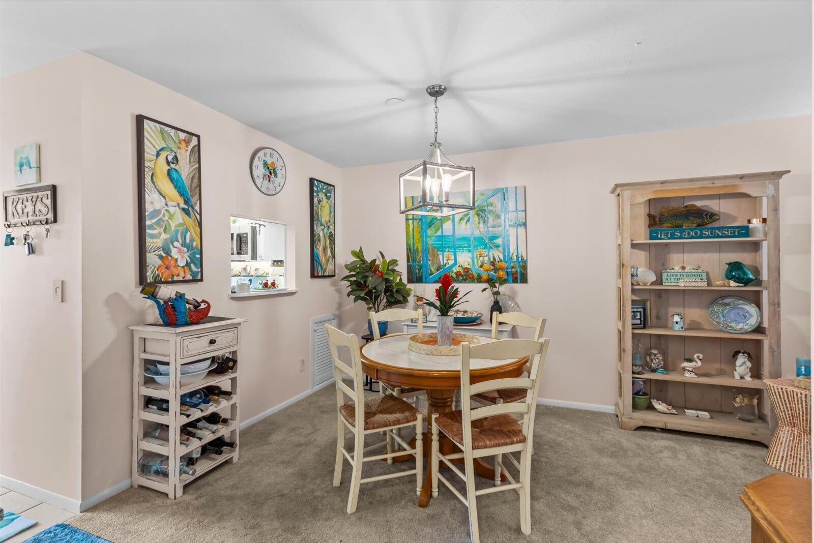 A dining room features a round wooden table, four chairs, a wine rack, and shelving — 2929 SE Ocean Boulevard # 9, Stuart FL 34996, STUART, FL