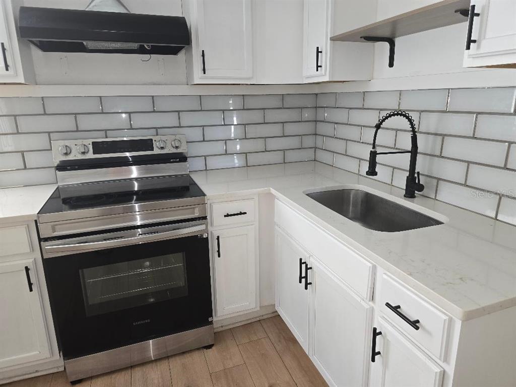 A kitchen features white cabinets, a stainless steel stove, a sink, and subway tile backsplash — 1847 19TH STREET S, ST PETERSBURG, FL