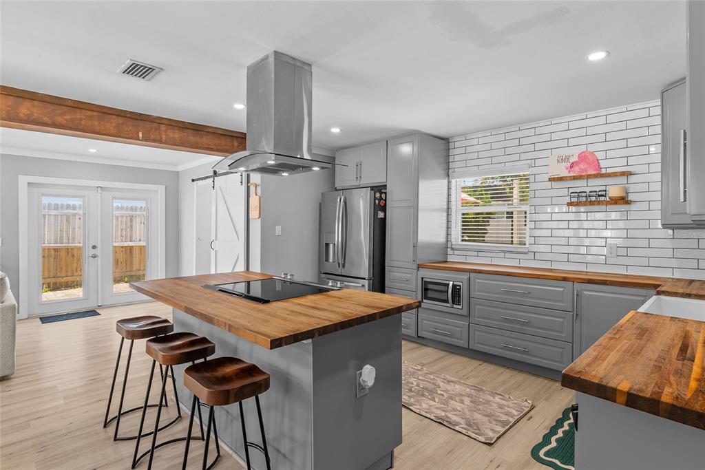 A kitchen features a wooden island with a stovetop, gray cabinets, and white subway tile — 3412 W BAY AVENUE, TAMPA, FL