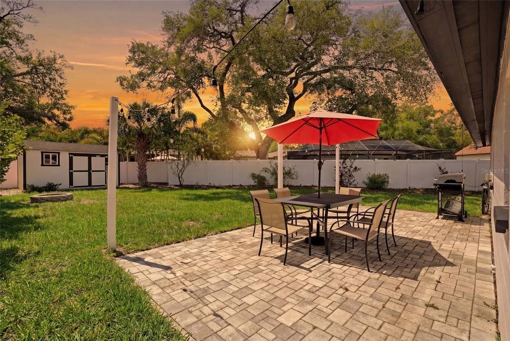 A backyard patio features a dining set with a red umbrella and a storage shed — 3412 W BAY AVENUE, TAMPA, FL