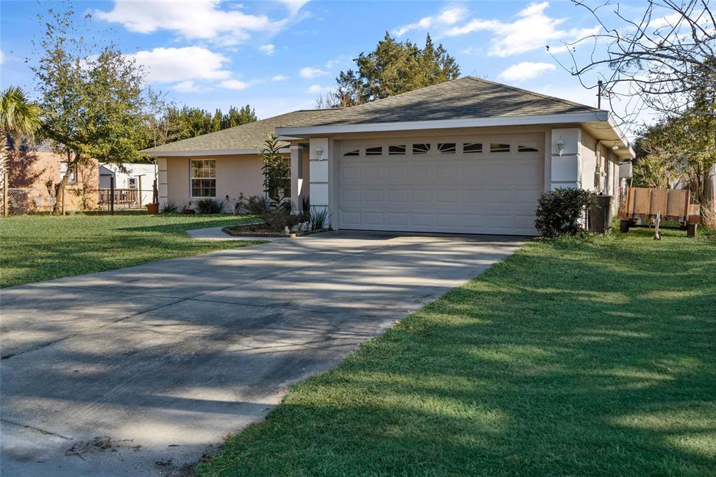 A single-story house with a beige stucco exterior, a two-car garage, and a concrete driveway — 11965 SE 70TH AVENUE ROAD, BELLEVIEW, FL