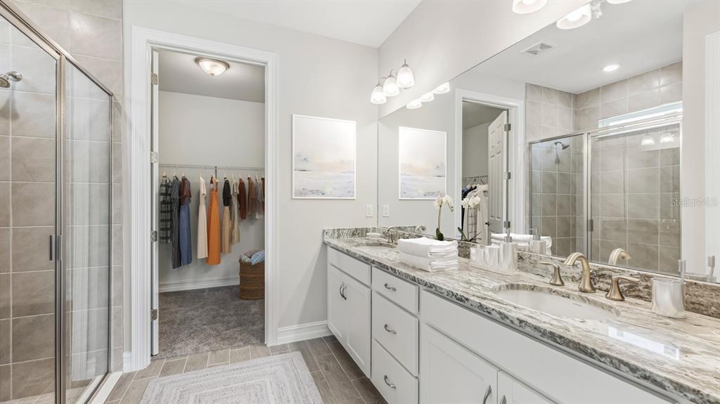 A bathroom with a double vanity, granite countertops, a glass shower, and an attached walk-in closet — 26296 CORAL LAKES DRIVE, PUNTA GORDA, FL