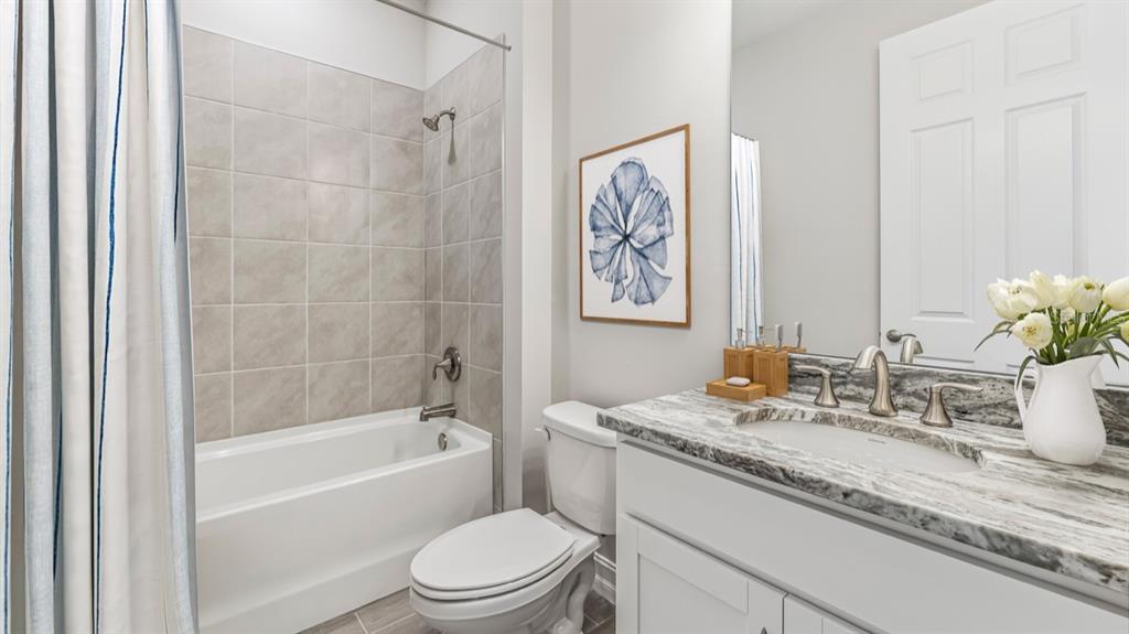 A bathroom features a tiled shower-tub combo, a white toilet, and a granite-topped vanity — 26296 CORAL LAKES DRIVE, PUNTA GORDA, FL