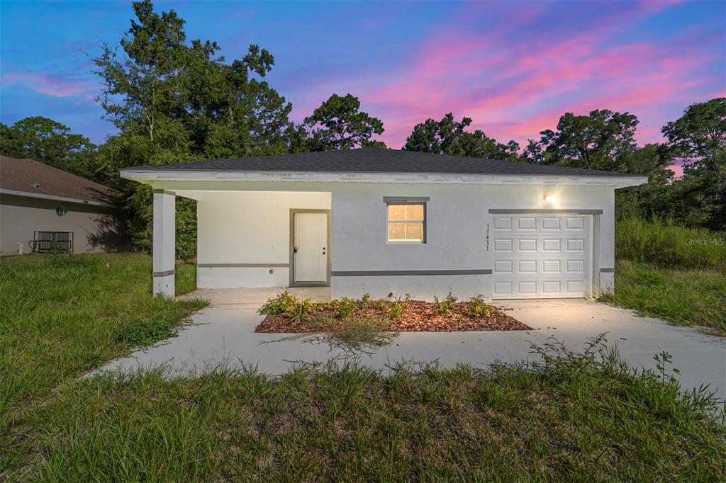 A single-story house with a white stucco exterior, a garage, and a covered front porch — 15431 SOUTHWEST 41ST STREET ROAD, OCALA, FL
