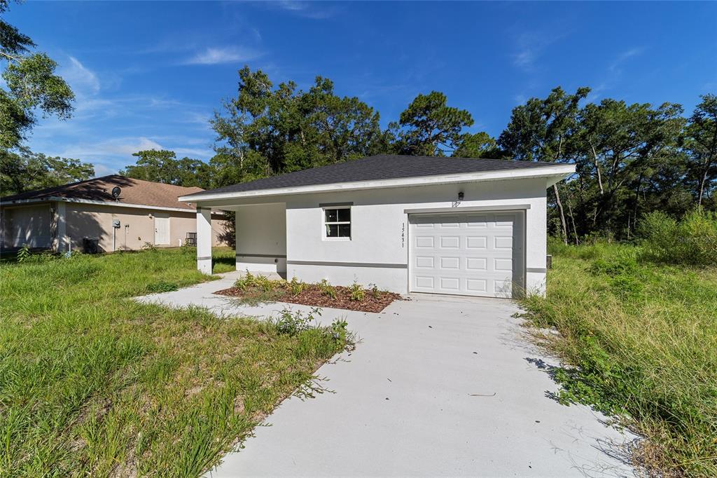 A white, single-story house with a garage and a concrete driveway sits on a grassy lot — 15431 SOUTHWEST 41ST STREET ROAD, OCALA, FL