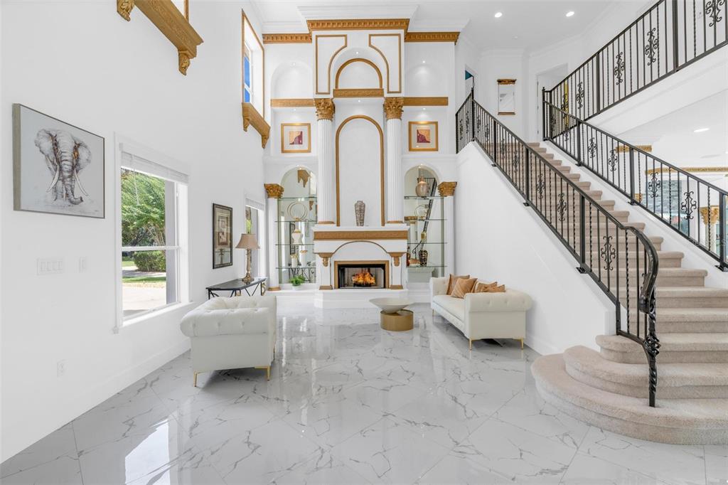 A grand foyer features white marble floors, a fireplace, and a staircase with iron railings — 9656 WEATHERSTONE COURT, WINDERMERE, FL