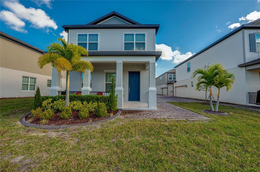 A two-story house with a blue front door, a covered porch, and palm trees — 2912 MELETO BOULEVARD, NEW SMYRNA BEACH, FL
