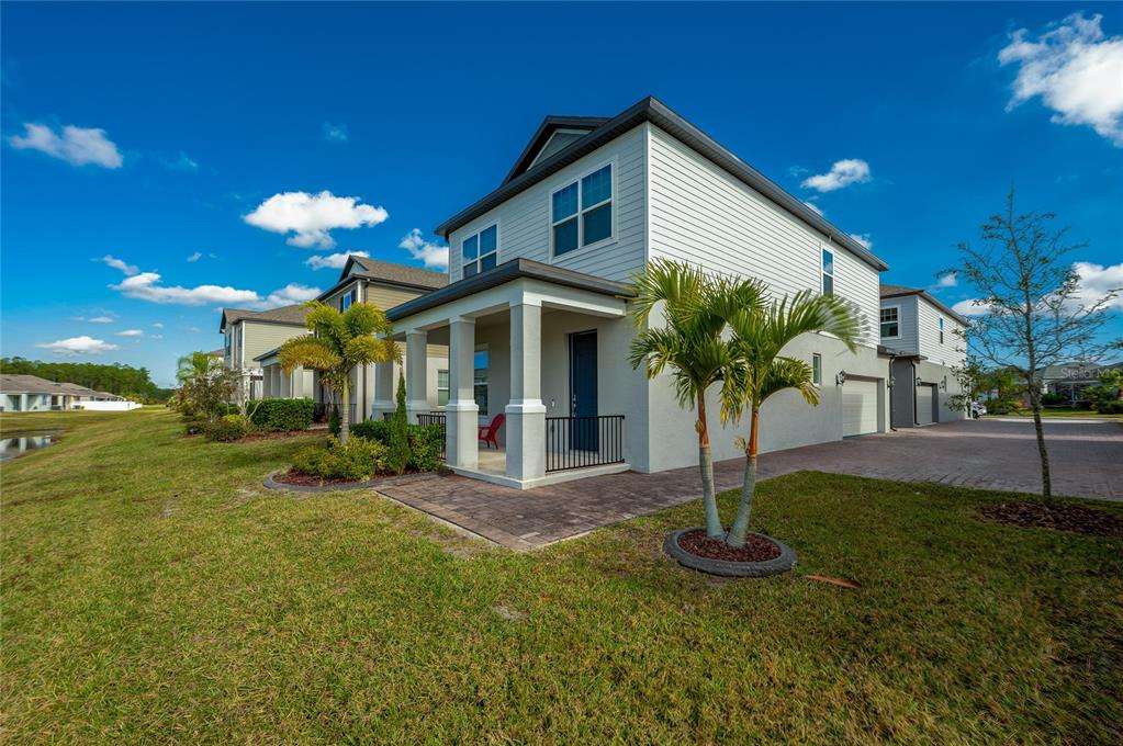 A two-story house with a covered front porch, light siding, and a paved driveway — 2912 MELETO BOULEVARD, NEW SMYRNA BEACH, FL