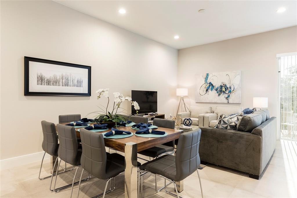 A dining area with a wooden table and grey chairs sits beside a living room — 7546 SUNVILLE AVENUE, KISSIMMEE, FL