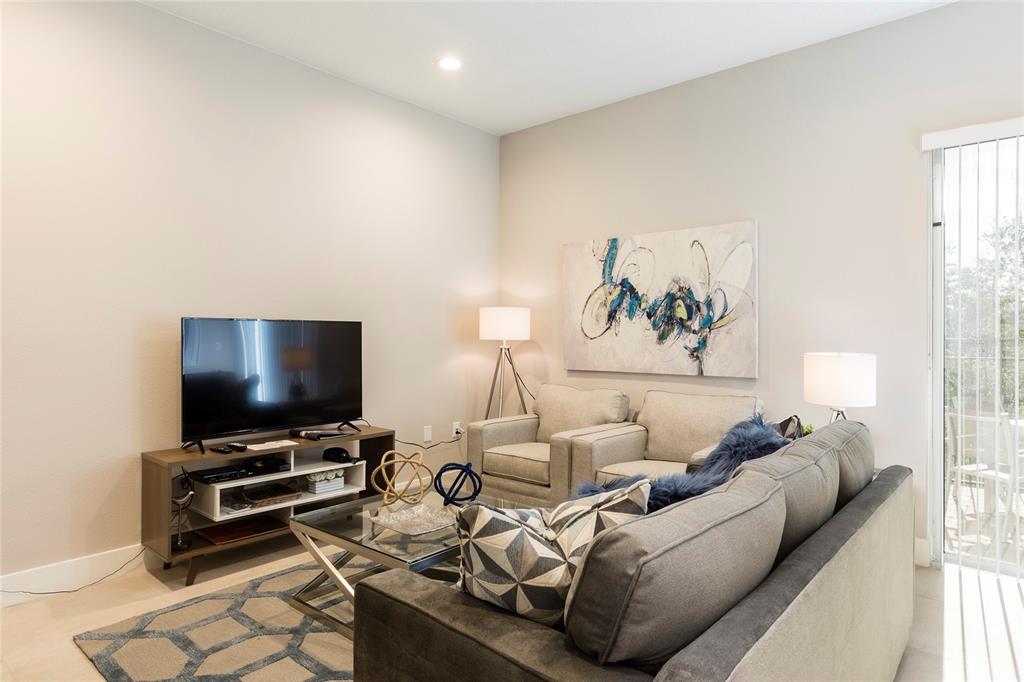 A living room features a television on a media console, two armchairs, and a sofa — 7546 SUNVILLE AVENUE, KISSIMMEE, FL