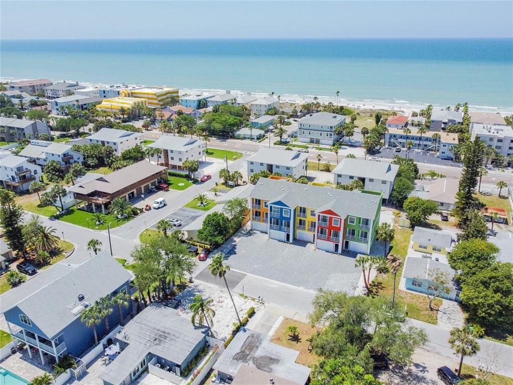 An aerial view shows a colorful multi-unit townhouse complex near a beach and ocean — 2108 1ST STREET, INDIAN ROCKS BEACH, FL
