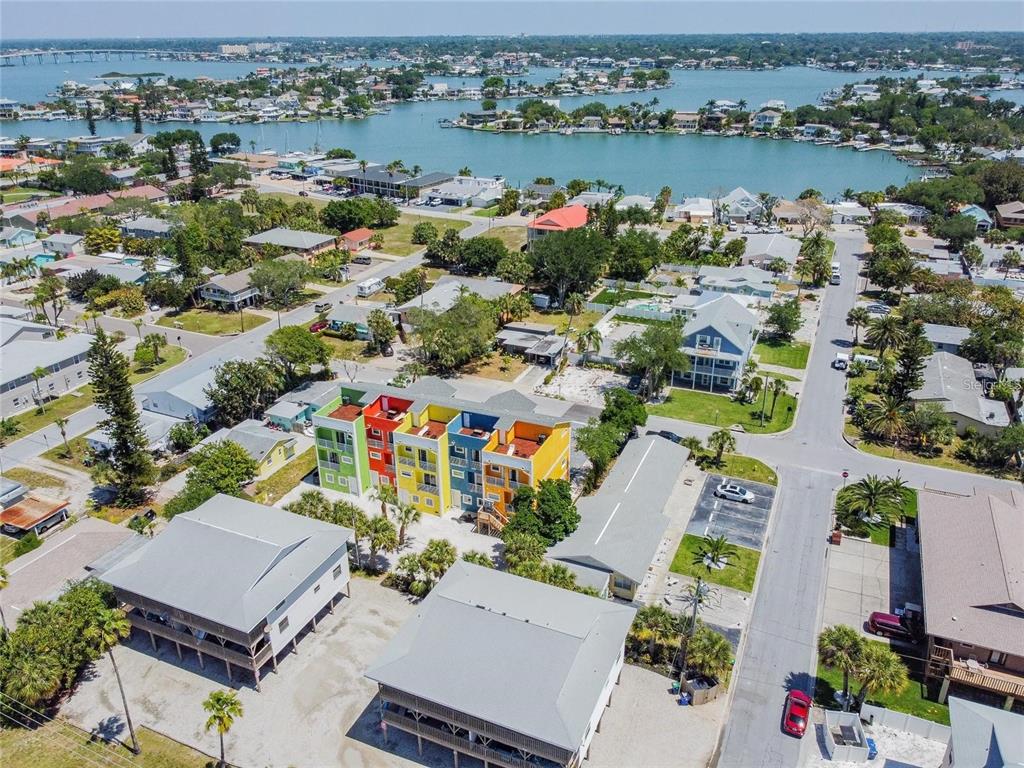 An aerial view shows a colorful multi-unit building surrounded by residential homes and a bay — 2108 1ST STREET, INDIAN ROCKS BEACH, FL