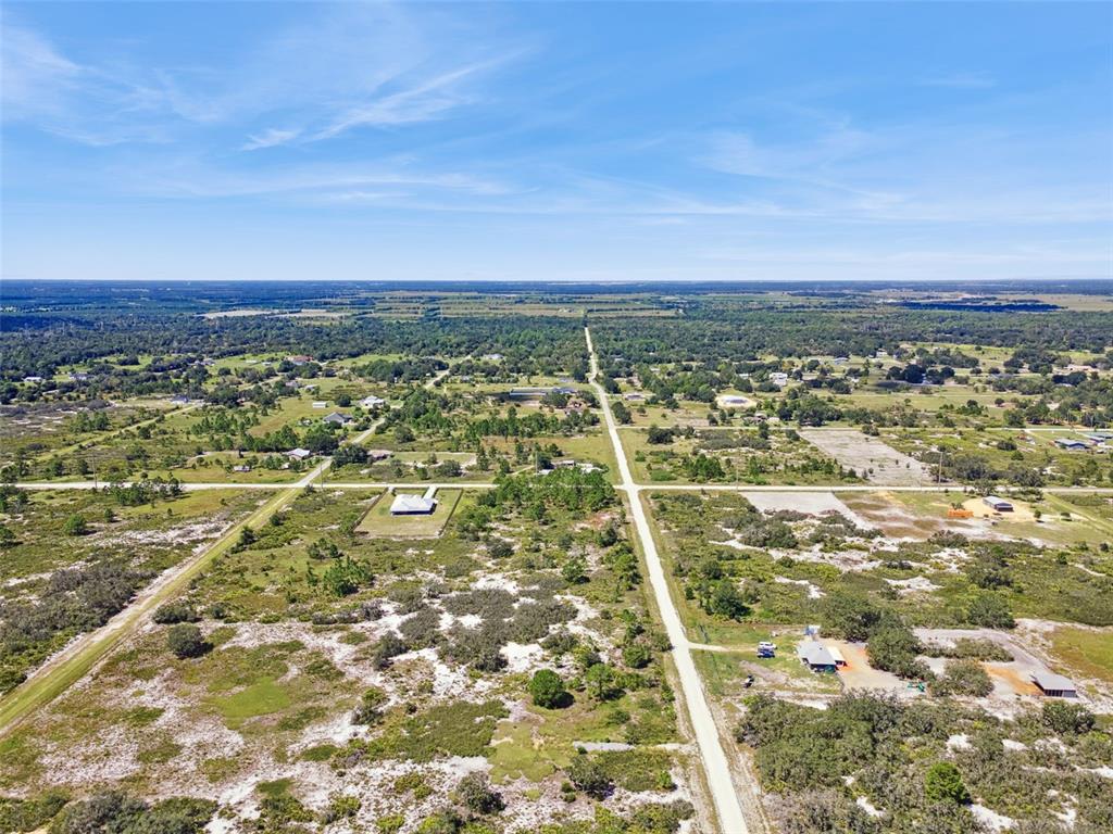 An aerial view shows a rural landscape with dirt roads, scattered houses, and vegetation — 2253 W SHULA ROAD, AVON PARK, FL
