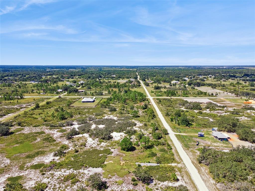 An aerial view shows a rural landscape with dirt roads, scattered trees, and sparse houses — 2253 W SHULA ROAD, AVON PARK, FL