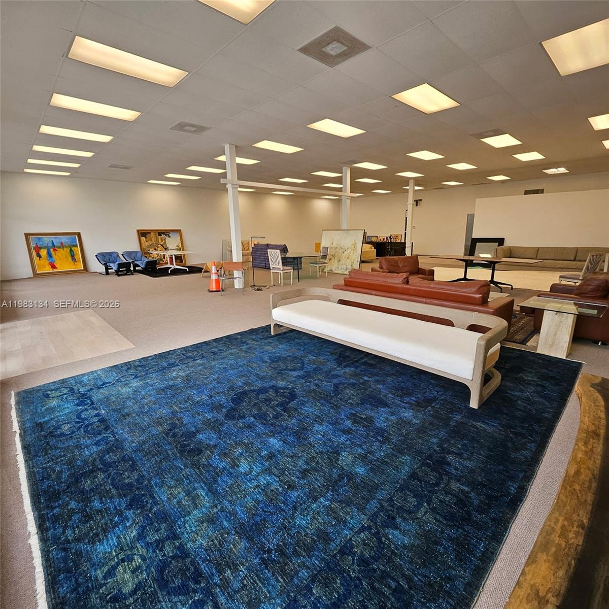 A large, open-plan showroom features a blue area rug, various furniture pieces, and recessed lighting — 2025 13th Ave, FL 32960, FL
